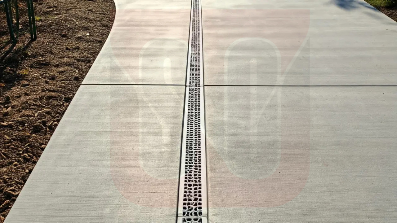 Concrete driveway with a drainage grate and stone pavers